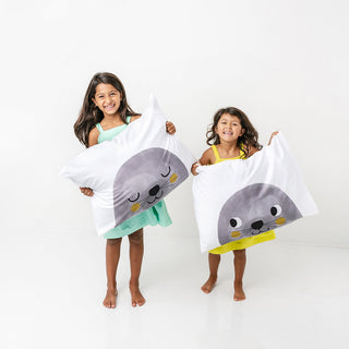 Two children holding towels with seal designs on a white background