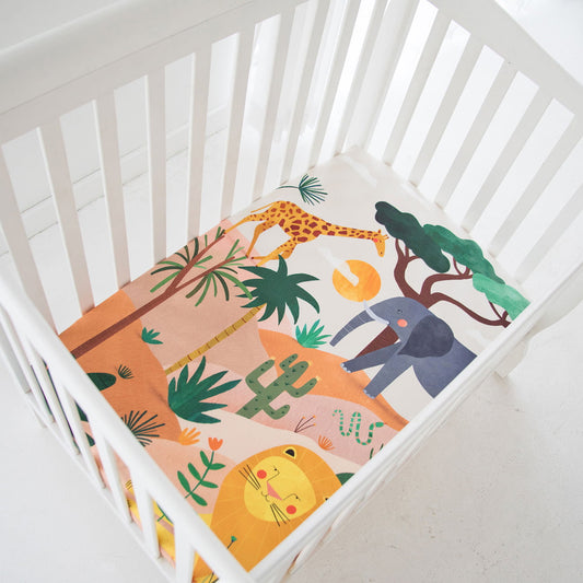Crib with a colorful safari-themed blanket featuring animals and plants.