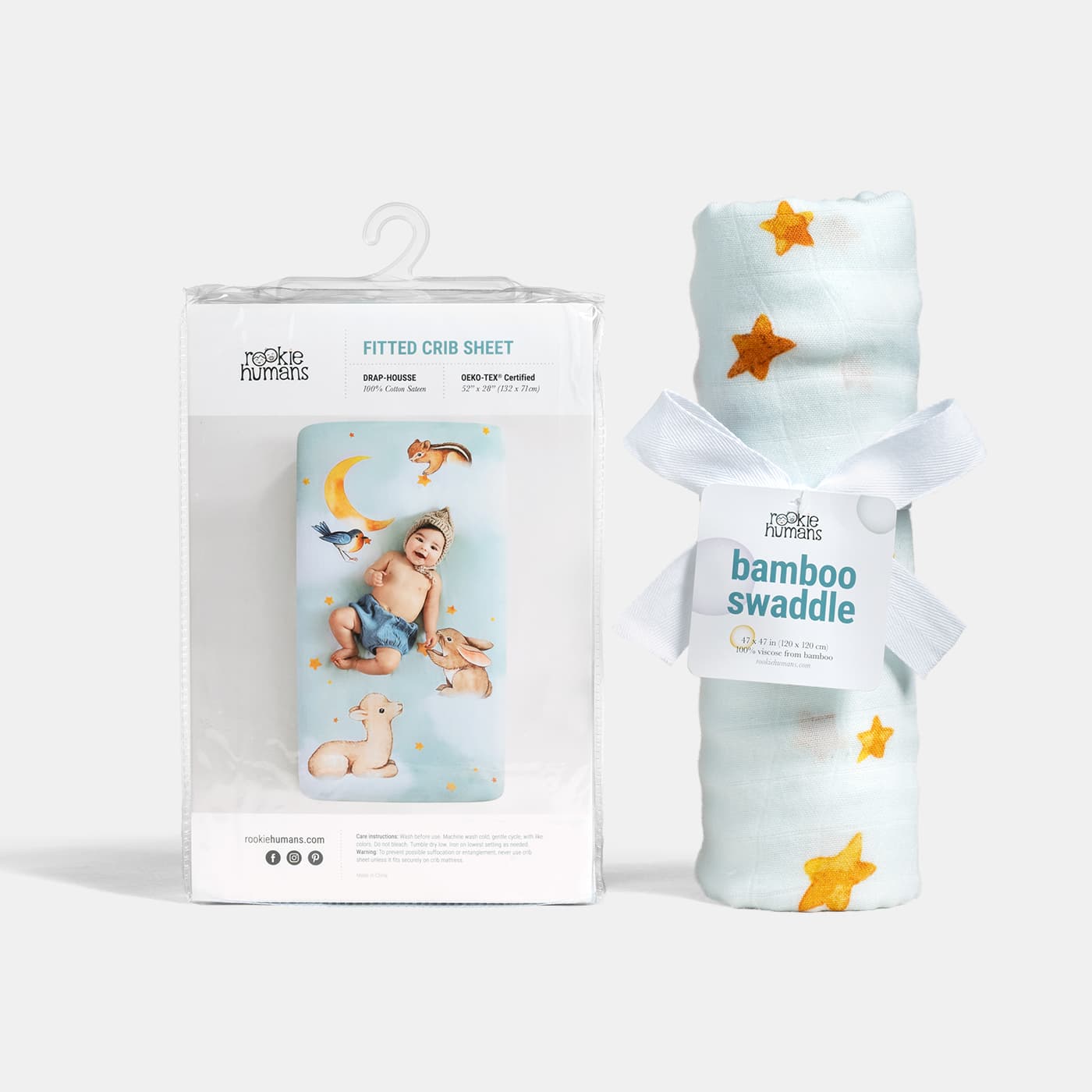 Baby swaddle and fitted crib sheet with packaging on a white background