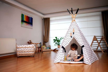 Child playing inside a teepee in a room with toys and furniture.